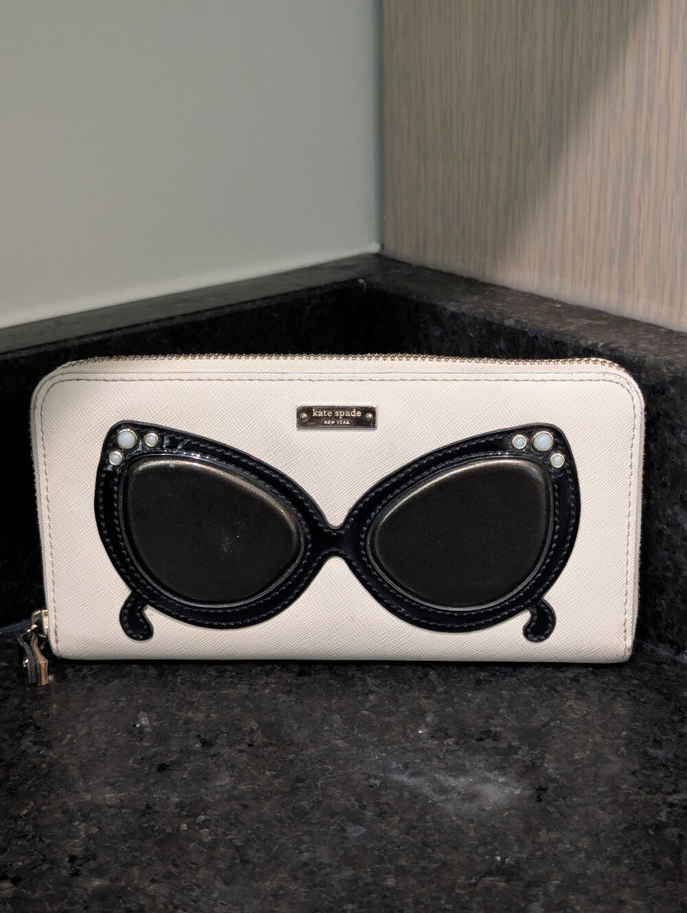 Kate Spade cream zip-around wallet with black sunglasses applique